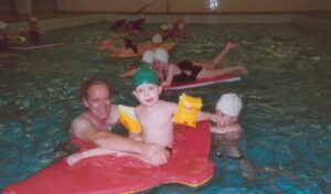 Old image of Head coach in the pool teaching beginners
